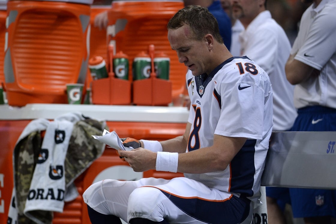 Former Broncos quarterback Peyton Manning reading a playbook in 2014