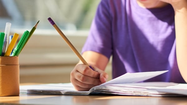 oung child sitting at a table learning and completing school work.
