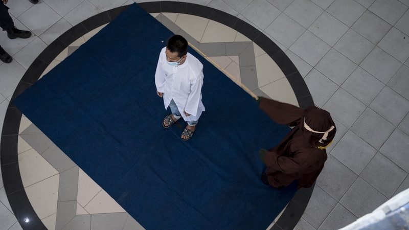 The men, who were not identified, were whipped with a rattan by a masked sharia officer