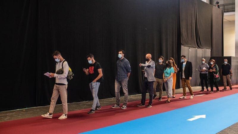 Participants observe social distancing guidelines as they stand in a queue during a job and employment fair in Barcelona