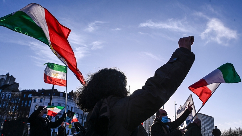 People gesture and wave former flags of Iran as they protest outside the Antwerp criminal court