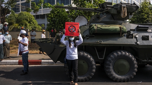 Protesters hold banners and shout slogans in front of Myanmar soldiers and armoured vehicles in Yangon, Myanmar