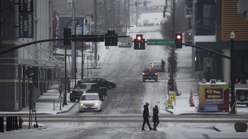 People cross a road in Nashville, Tennessee, after an overnight mix of sleet and freezing temperatures coated the city in ice