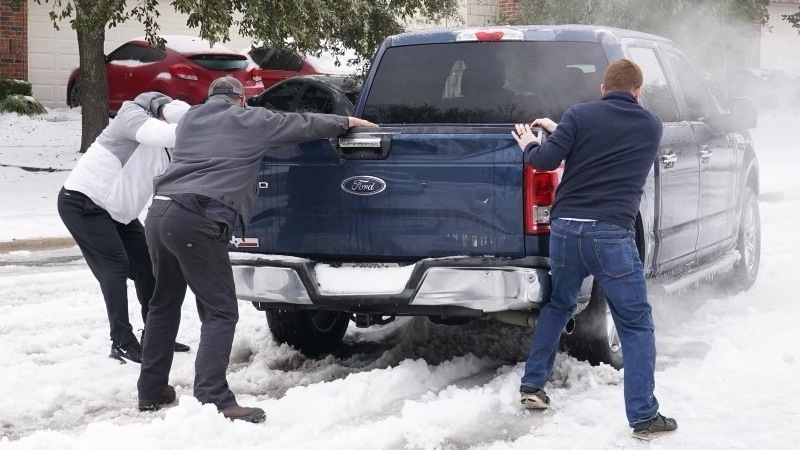 People help push a pickup stuck in the snow at Round Rock, Texas