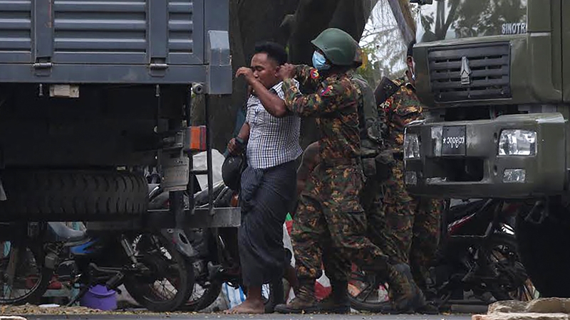 A protester is led away after being detained by security forces in Mandalay