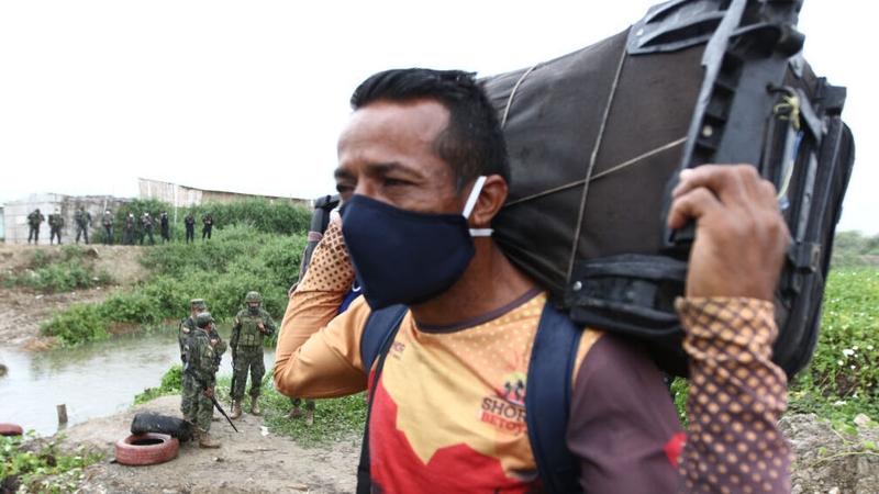 A Venezuelan migrant holds his suitcase on his back as he attempt to cross from Peru into Ecuador (file pic)
