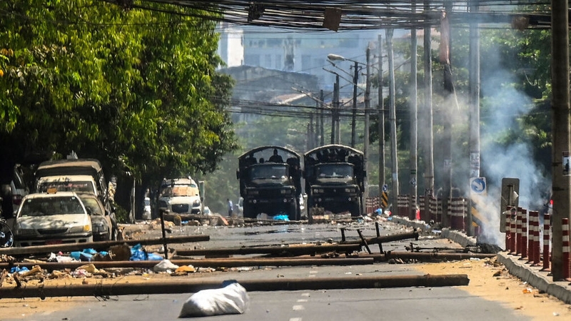 Military trucks are seen near the remains of a barricade erected by protesters in the city of Yangon