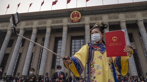 A delegate wears traditional clothing as she takes a selfie after the closing session of the China National People's Congress in Beijing