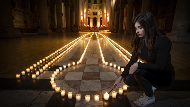 Holly Wilson, whose grandmother Ada Wilson died during the pandemic, lights a candle in Belfast Cathedral this evening