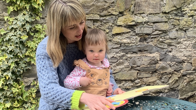 Dairíne McCafferty reads to her one-year-old daughter Riadh McCafferty Brannigan