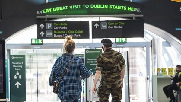 A member of the Defence Forces escorts a passenger from the Terminal 2 arrivals hall at Dublin Airport