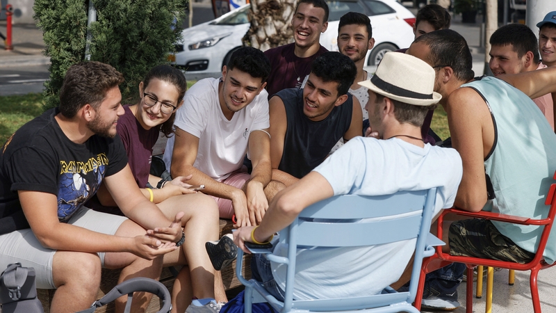 Youths gather on a street in the Israeli coastal city of Tel Aviv after authorities announced that face masks were no longer needed outside