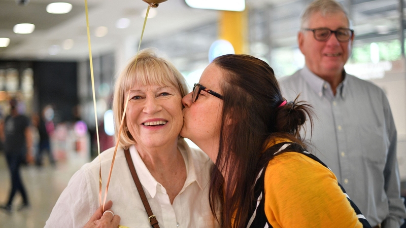 A family reunites after a flight from New Zealand lands at Sydney International Airport