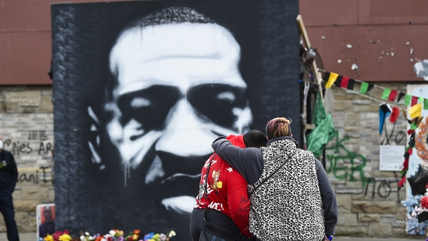 A couple pause for a moment in front of a portrait of George Floyd in Minneapolis today