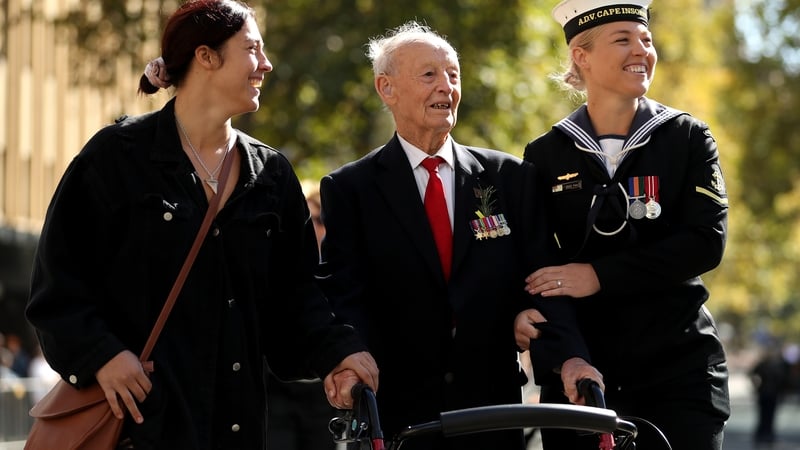 A war veteran is assisted as he walks down Elizabeth Street during the ANZAC Day parade in Sydney