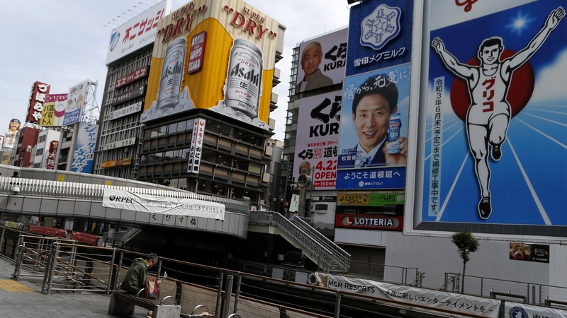 A man wearing a mask sits a bench at almost empty Dotonbori, one of Osaka's most popular tourist areas
