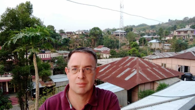 Is as Corcaigh ó dhúchas d'Fhionnbarra Ó Buachalla agus tá sé ag cur faoi in Mizoram in Oirthuaisceart na hIndia