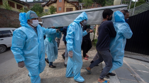 Relatives of Covid-19 victim wear protective clothing during a funeral procession in Srinagar