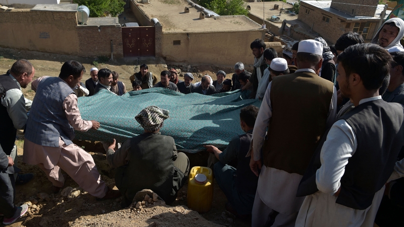 Shiite mourners lower the body of a girl, who died in yesterday's school blast, at a cemetery in Kabul
