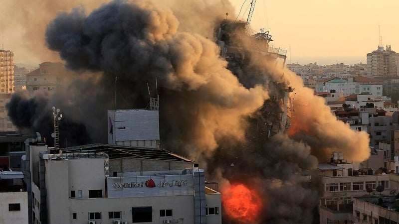 Heavy smoke and fire surround Al-Sharouk tower in Gaza City as it collapses during an Israeli air strike