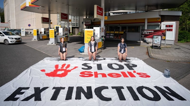 Protesters stained in a coloured vegetable oil join a protest at a Shell gas station in The Hague