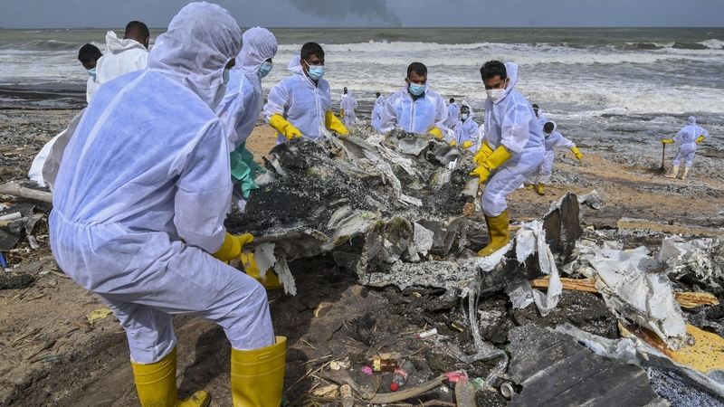 Members of the Sri Lankan navy work to remove debris washed ashore