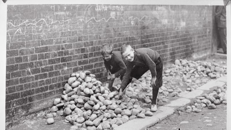 Children gather stones on the streets of Belfast, circa 1920. Photo: Getty Images