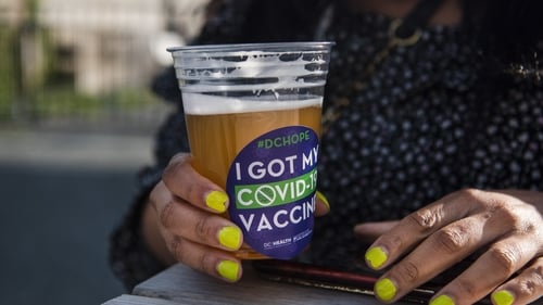 A woman drinks a free beer after receiving her vaccine in Washington DC