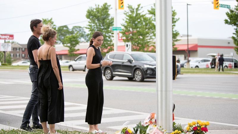 People pay their respects at the scene where a man driving a pickup truck killed four members of a family in Ontario