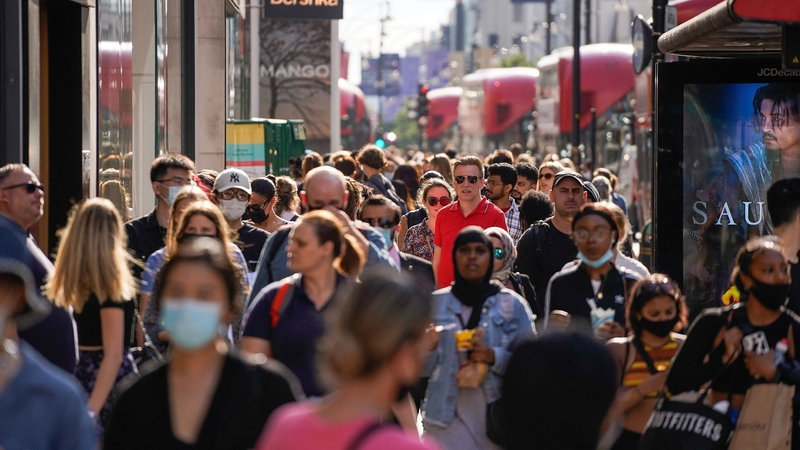 Pedestrians, some wearing face coverings due to Covid-19, walk past shops on Oxford Street in central London