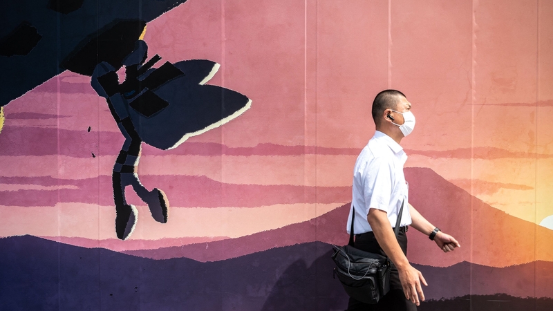A pedestrian walks past signage of the Tokyo 2020 Olympic and Paralympic Games outside a construction site in Tokyo