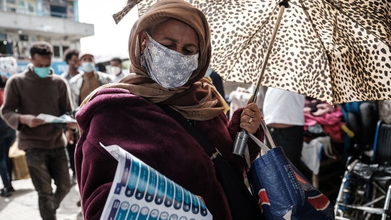 A woman looks at a paper showing a list of political parties for the upcoming general election under an overpass in Addis Ababa