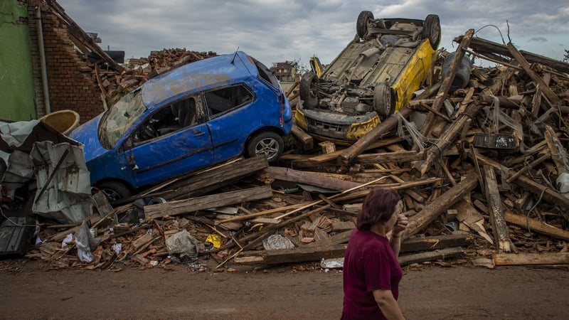 A woman walks past damaged cars after the tornado hit the village of Mikulcice