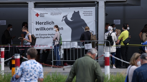 People stand in line to be vaccinated at Berlin's former Tegel airport in Germany today