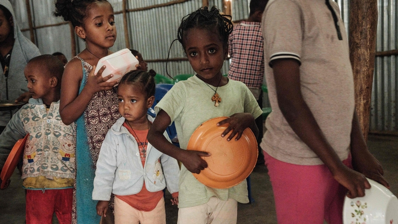 Children, who fled the violence in Ethiopia's, Tigray region, wait in line for