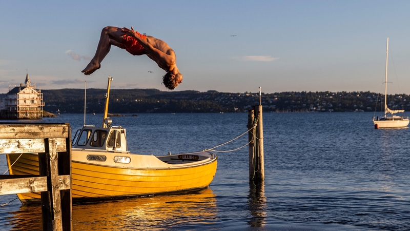 A man somersaults into the fjord for an evening swim on Lindoya island in Oslo
