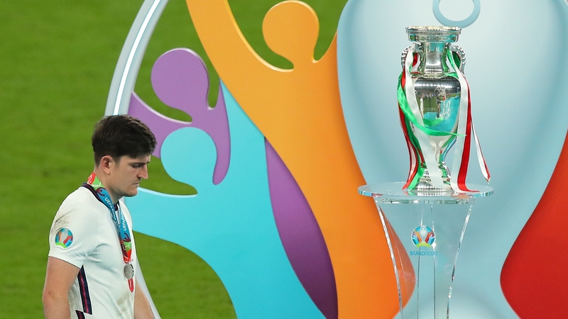 A dejected Harry Maguire walks past the Euro 2020 trophy