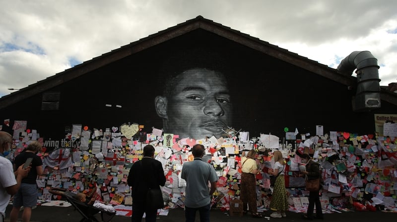 People at a mural of English footballer Marcus Rashford in Manchester which was defaced with abusive graffiti after the Euro 2020 final. Photo: Getty Images