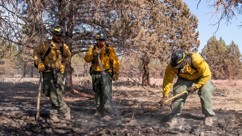 Oregon firefighters Taryn Thomas, Kenny Picard and Gamari Griffin work on a hotspot on the fire perimeter of the Bootleg Fire