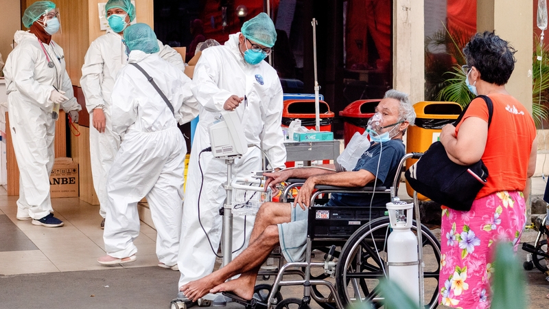 A patient with Covid-19 sits in a wheelchair outside the Bekasi Public Hospital in West Java