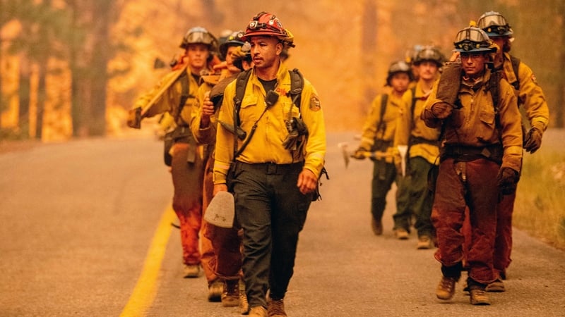 Firefighters walk along a road while working the scene during the Dixie fire in the Prattville community of unincorporated Plumas County