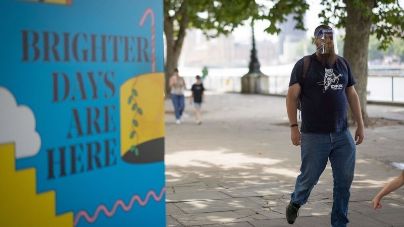 A pedestrian walks past a coraonvirus sign in London