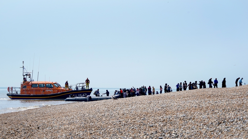 Migrants are watched over by the RNLI as they make their way up the beach in Kent