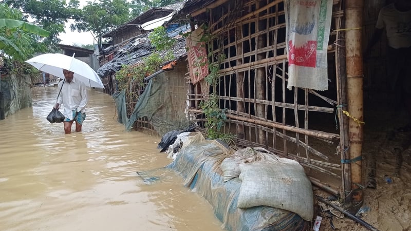 A man walks through flood waters in the camp
