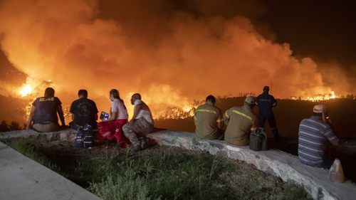 People watch the wildfires as they wait to be evacuated from Evia