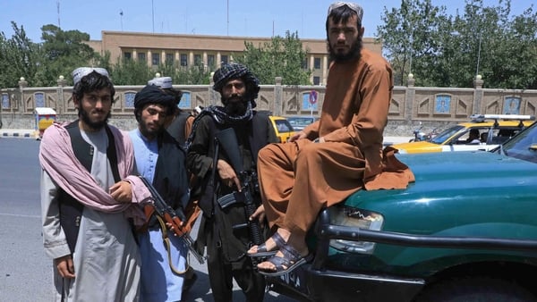 Taliban fighters stand guard along the roadside in Herat