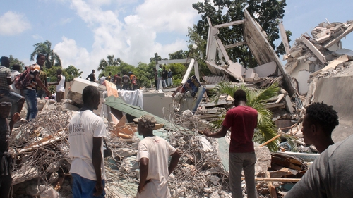 People search through the rubble of what used to be the Manguier Hotel in Les Cayes