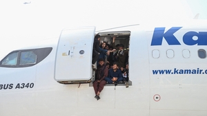 Afghan people climb into a plane and sit by the door as they wait at the Kabul airport