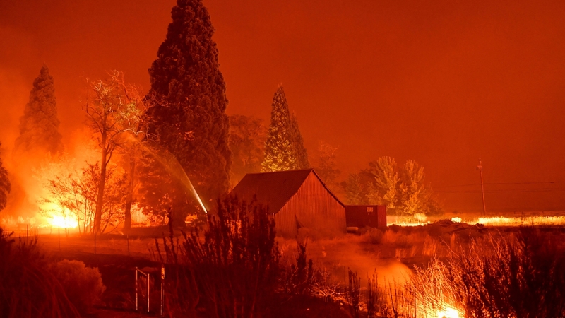 Firefighters use a hose line to extinguish hot spots during the Dixie Fire near Janesville