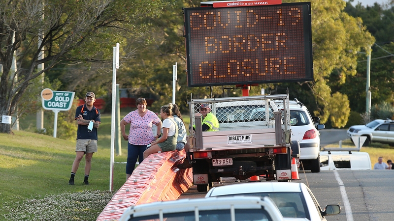 People talk to each other over the barriers at the Queensland-New South Wales border between the Gold Coast and Tweed Heads